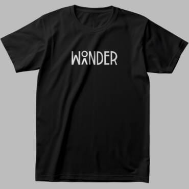 Black travel-themed t-shirt with "WONDER" typography, where the "O" is shaped like a mountain and traveler icon, representing adventure, trekking, and exploration.