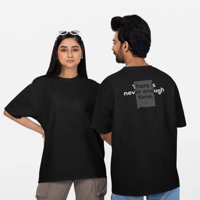 Oversized unisex black t-shirt with a minimalist text print on the back reading "There is never enough time," worn by a male and female model.