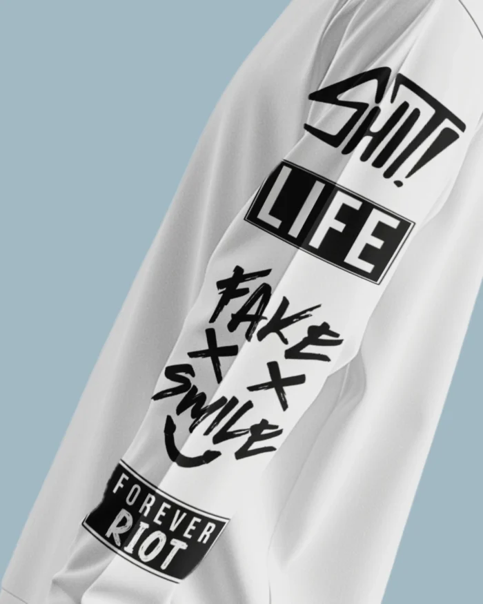 Sleeve Close-Up of Bold Graffiti Text “Shit Life Fake Smile Forever Riot” on White Sweatshirt