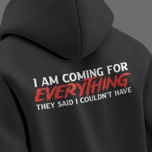 Black oversized hoodie with bold quote on back reading “I AM COMING FOR EVERYTHING THEY SAID I COULDN’T HAVE” in white and red typography.